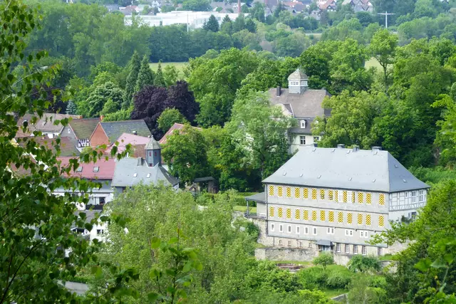 Links ist die alte Kirche zu sehen, hinten in der Mitte das Neue Schloss und vorne rechts das heutige Schloss im barocken Stil, das zur Talseite vier Stockwerke hat.
