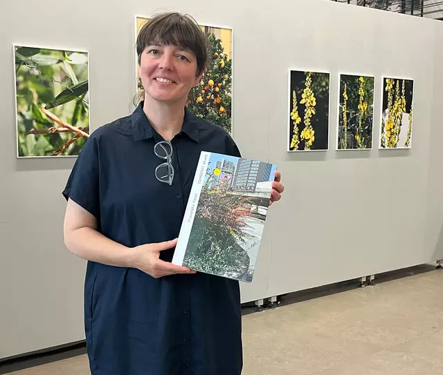 Die Fotografin Franziska Klose mit einem Ausstellungskatalog inmitten ihrer Bilder in der GAF.