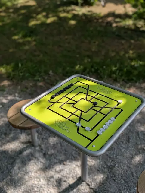 Auch der Denksport kommt hier nicht zu kurz – an zwei festinstallierten Spieltischen kann im Schatten der Bäume „Mühle“ und „Vier gewinnt“ gespielt werden. Hier wurden bewusst je Tisch nur zwei Sitzgelegenheiten fest installiert; die jeweils freigehaltenen Tischseiten bieten Platz zur Anfahrt und Aufstellung von Rollstühlen, Buggys oder Rollatoren. | Foto: Denise Hartmann