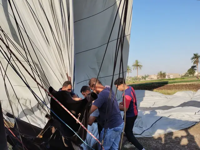 Zum ersten Mal erlebe ich eine Landung mit dem Heißluftballon, bei dem der Fahrkorb nicht umgekippt ist. - Helfer machen die Ballonhülle für den Transport mit einem Kleintransporter fertig.

