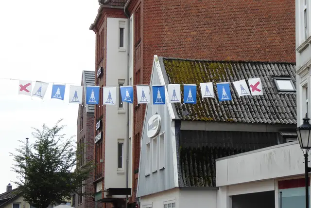 Auf der Werbegirlande in der Fußgängerzone ist als weiteres Wahrzeichen die Kugelbake in Blau und Weiß zu sehen.