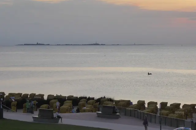 Am Abend: Vorne die Duhner Strandpromenade, hinten in der Nordsee die Insel Neuwerk.