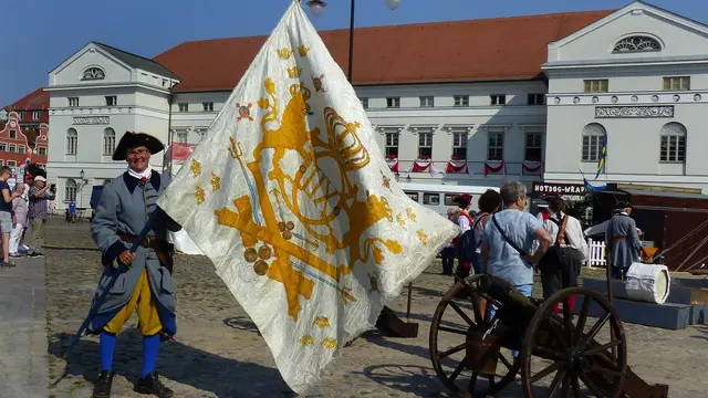 Ein Teilnehmer des schwedischen Lagers präsentiert auf dem Marktplatz die historische „Waffenfahne“. Foto: Helmut Kuzina
