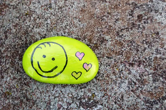 Ein freundlich lächelndes Gesicht wird von drei Herzen begleitet.