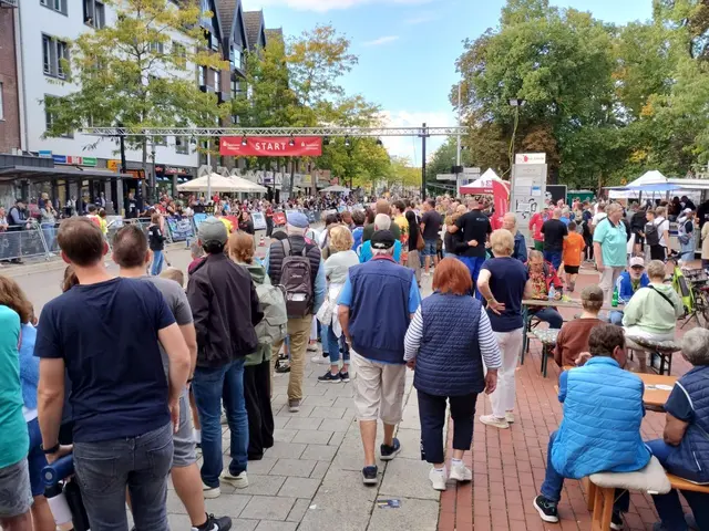 Zuschauer warten auf den Zieleinlauf der 2-km-Läufer/innen auf der Burgdorfer Straße.
