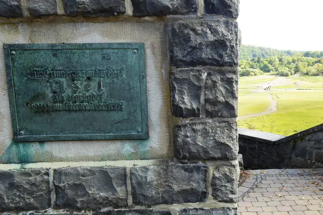 "Zur Erinnerung an das Dorf / Asel / gegründet 1317 / 1914 vom Edersee überflutet". Rechts ist die Aseler Brücke erkennbar.