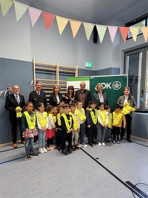 Übergabe der Sicherheitswesten an der Löweneck Grund- und Mittelschule Augsburg durch v. l. Karl-Heinz Knerndel, stellv. Vorsitzender der Verkehrswacht, Stefan Speer, stellv. Polizeipräsident, Sabine Beck, Regierungsvizepräsidentin, Birgit Löffler Moody, Schulleiterin, Alfred Heigl, Direktor der AOK Augsburg, Eva Weber, Oberbürgermeisterin der Stadt Augsburg, Marianne Birkle, Vertreterin der Landesverkehrswacht. | Foto: Veronika Murr, AOK Bayern