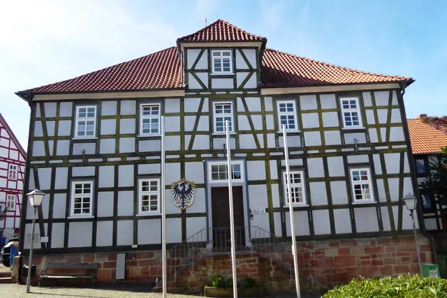 Das 1823 errichtete  Rathaus der Stadt Gemünden. Auf dem Bild links vom Eingang ist das Gemündener Wappen zu sehen. „Im silbernen Schild ein Schwarzer Adler mit Ziegenkopf, unter den Flügeln je ein goldener Stern.“ Der Ziegenkopfadler ist ein Symbol der Grafen von Ziegenhain, zu deren Besitz Gemünden ursprünglich gehörte. 