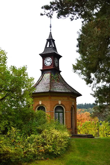 Der 2016 sanierte Uhrenturm. Die Uhr kann man auch vom Ort aus sehen. Dahinter eine kleine Weinberganlage.