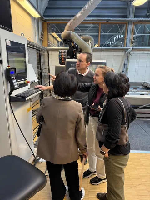 Besuch am BSZ Landsberg am Lech - Fachlehrer erklärt E. Ishekeeva und G. Usupova eine moderne Holzbearbeitungsmaschine in der Schreinerabteilung.