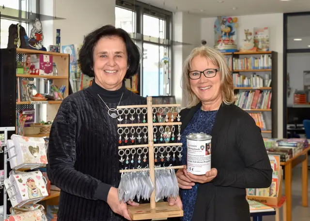 Foto: Marion Schmid (rechts) übergibt stolz ihren Aufsteller mit den Engelchen an Buchhändlerin Elke Eser im Buchladen in Meitingen.