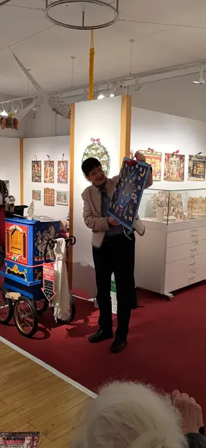 Privatsammlerin Manuela Weiss stellt während ihrer Führung eine Neuerwerbung aus Schwabmünchen vor: Den Zettelkalender „Weihnachten bei den Kindern der Welt“ des Verlags Coppenrath. Ein paar Ständchen auf der Drehorgel (links) durften bei der Eröffnung auch nicht fehlen.  | Foto: Alina Krüger