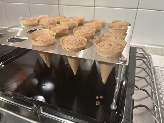 Diese Backform besorgte Georg Lipp extra für die Weihnachtsbäumchen. In den Tüten aus Backpapier wurde dann der Lebkuchen-Biskuit im Backofen gebacken. Anschließend kam mit weißer Kuvertüre und den gemahlen Pistazien als Hülle. Verzeirt noch mit getrockneten Johannisbeeren und Puderzucker - Ein richtiger Weihnachtsbaum. | Foto: Klaus Hill