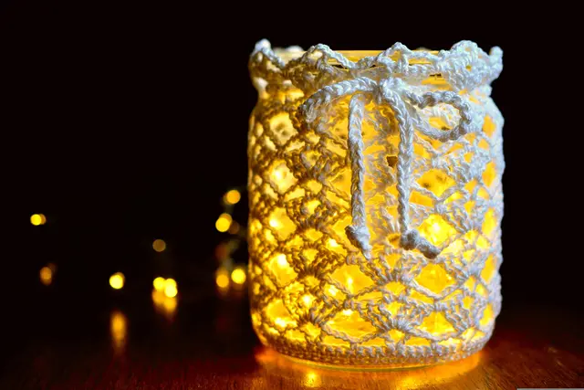 Ein umhäkeltes Einweckglas mit Lichterkette.