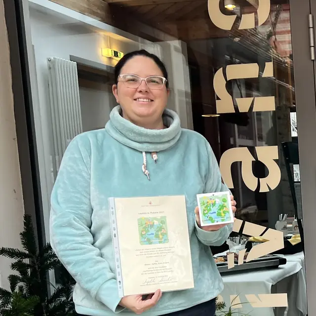 Die Leiterin des »Divano - Kaffee, Kunst &amp; Spirit« in Friedberg, Stefanie Widmann, konnte - gemeinsam mit dem Initiator der Aktion, Agraringenieur Ulrich Mück - in Augsburg die „Laudato-si“-Plakette 2025 in der Kategorie „ökologische Bildung“ entgegennehmen. Einen gut sichtbaren Platz im Divano hat Stefanie Widmann für die Plakette schon im Auge.  | Foto: P. Steffen Brühl