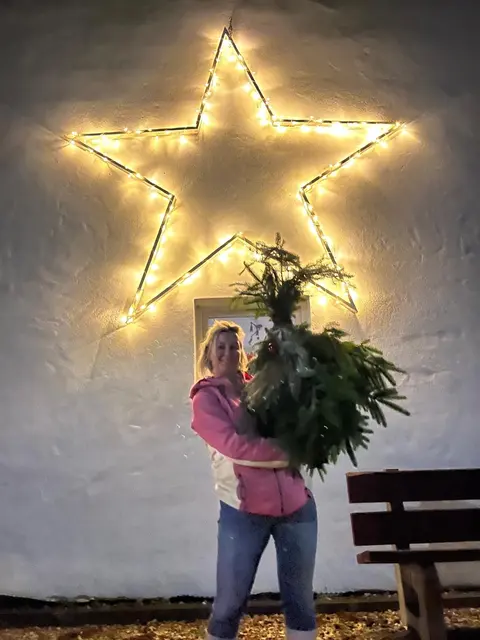 Foto: Stolz zeigt Anita Deisenhofer einen ihrer Wichtel, hergestellt mit Tannenzweigen aus dem eigenen Wald. 