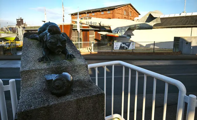 Skulptur am Südstrand, dahinter ein ausgestelltes Flugzeug | Foto: Shima Mahi