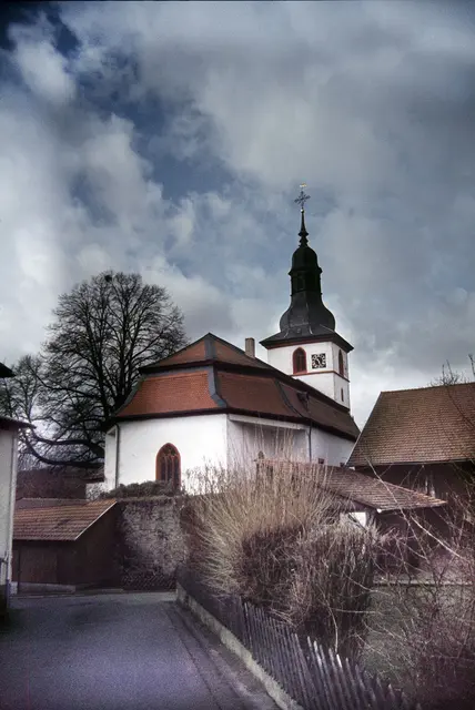 Die Kirche von Kirchbrombach steht an der Stelle einer alten Burg. Nur ein Teil der ehemaligen Burgmauer blieb erhalten und umgibt noch das Gotteshaus.