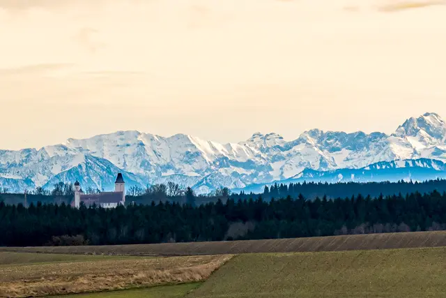 Schloss Hofhegnenberg vor den Alpen.