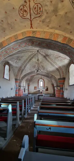 Der Kirchensaal aus zwei Jochen und einem gerade geschlossenen Chor.
Die Deckenmalerei mit vielen Ornamenten mit stilisierten Blüten, Blätter und Bäumen.