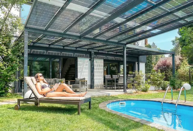 Während die Sonne dank der Premium Solarglasmodule im Dach der Solarterrasse für Strom sorgt, relaxen die Bewohner unter der hochwertigen Überdachung – die bei Bedarf sogar den eigenen Pool überspannt.  | Foto: HLC/Solarterrassen &amp; Carportwerk GmbH