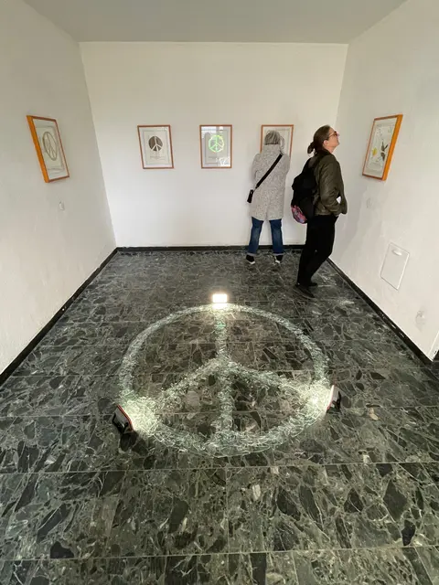 Heicappel zeigt verschiedene Perspektiven auf und auch Impressionen aus verschiedenen Erdteilen.  Jedes Werk trägt ein treffendes Zitat zu dem Thema.  Ein 3-seitiger Katalog mit diesen Zitaten stellt der Künstler zusätzlich dem Besucher bereit.  Highlight ist das PEACE-Zeichen aus tausenden Glassplittern auf dem Marmorboden aufgeschichtet und giltzernd angestrahlt. | Foto: Andreas Ingramm, AIRL-Lab KKRR