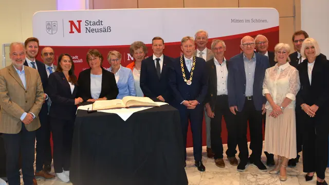 Geehrte und verabschiedete Stadträte und Stadträtinnen tragen sich in das goldene Buch der Stadt Neusäß ein.