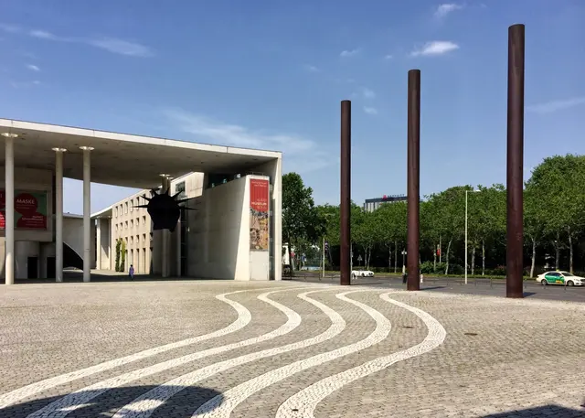 Blick von der Bundeskunsthalle auf das Kunstmuseum Bonn. Die Stelen (insgesamt 16) stehen für die 16 Bundesländer. Die Bodengestaltung des Vorplatzes greift die wellenförmige Fassade der Bundeskunsthalle auf.   | Foto: copyright Margot Klütsch