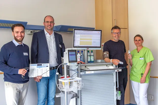 (v.re.) Die Pflegefachkraft Martina Maier zeigt Martin Gösele, dem Vorstand der Wertachkliniken, wie die Messung der Vital-Werte mit den neuen Spot-Monitoren funktioniert. Federführend bei der Digitalisierung der Vital-Werte-Erfassung waren Daniel Hierl, Pflegedienstleiter und Projektleiter KHZG (Krankenhauszukunftsgesetz) an den Wertachkliniken, sowie Samuel Schiele, Bereichsleiter Pflege Care, der mit dem Scanner einen Barcode auf dem Papierbogen eines Patientenarmbandes scannt, das für den Klinikvorstand als Musterpatienten ausgestellt wurde.
 | Foto: Doris Wiedemann