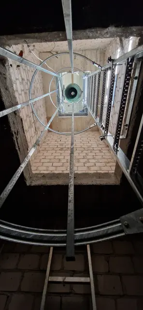Blick vom Boden des Glockenturms der Friedhofskapelle Breidenstein zur Glocke