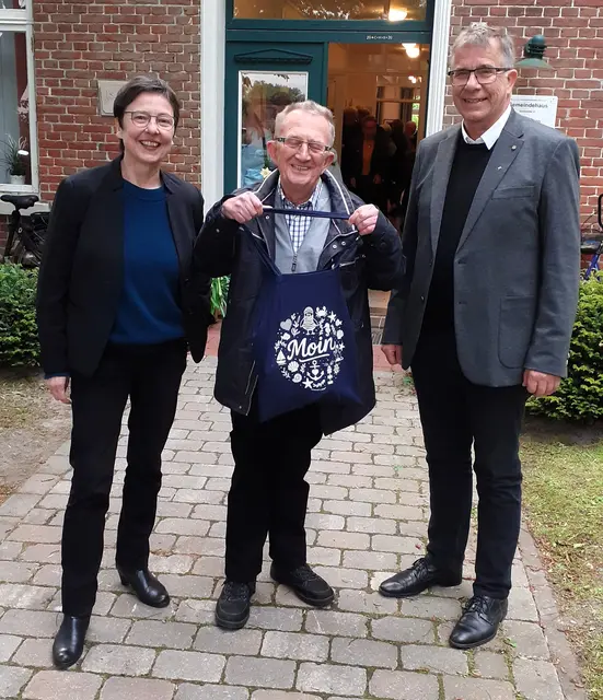 Das Foto zeigt Anke Claßen und Dietmar Reumann-Claßen mit dem Neumühler Presbyter Reiner Terhorst (Mitte), der den beiden Leckereien aus Ostfriesland und Duisburg und viel Dank überbringt.
Foto: Christoph Schultz
