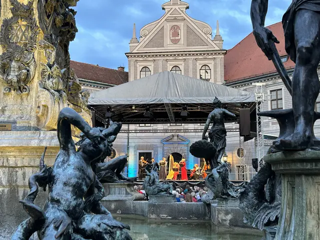 Nahaufnahme des Brunnenhofs in München, im Hintergrund spielt eine Gruppe Musizierender, im Vordergrund sind die Statuen im Brunnen zu sehen.