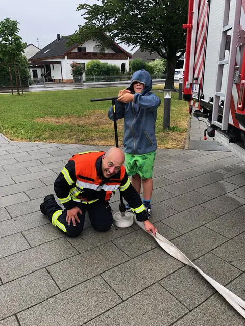 Foto: Feuerwehrmann Peter Bobinger (FFW Blankenburg) zeigt einem Schüler, wie ein Wasserschlauch fachgerecht aufgerollt wird.