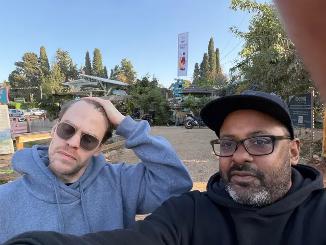 Zwei Männer machen ein Selfie in einem grünen Gartenlokal in Israel.