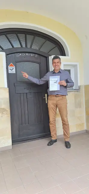Bürgermeister Ben Matthes vor der „Alten Schule“ in Wörleschwang. Die Plakette weißt auf die Wochenstube des Großen Mausohrs im Dachboden des Gebäudes hin. | Foto: Markt Zusmarshausen
