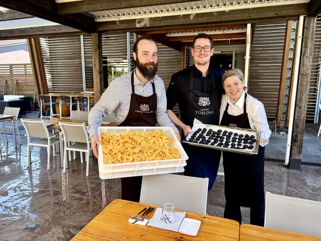 In der Mitte, ein Tablett mit tintenschwarzen Tortelli in den Händen, steht Sebastian Sartorelli selbst: Küchenchef der Hosteria Toblino in Sarche, mitten im Val dei Laghi – trotz deutscher Abstammung ein so unbedingter Kenner der Trentiner Bauernküche, dass sich seine Herkunft längst auf den Tellern aufgelöst hat. Neben ihm zwei seiner Mitarbeiter, auf der zweiten Wanne goldene Tagliatelle – zwei Farben, ein Ursprung: Beides wird hier, wie an jedem Tag, in derselben Küche von Hand gerollt.
 | Foto: Daniel J. Basler