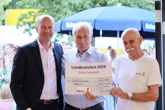 Landrat Martin Sailer (links) überreichte im Rahmen des Landkreisfestes 2026 einen Spendenscheck an den ersten Vorsitzenden Max Strehle (Mitte) und den zweiten Vorsitzenden Hans Jenuwein von mukis e. V.. | Foto: Julia Pietsch