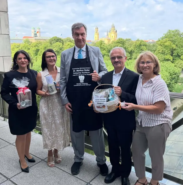 Von links nach rechts: Gülden Bayram (Chefredakteurin der Postzeitung Bayern), Leyla Diri (Vorstand), Bayerns Ministerpräsident Dr. Markus Söder, Arif Diri (1. Vorsitzender des Deutsch-Türkischen Freundschaftsvereins Bobingen) und Kadriye Diri (Vorstand). Im Rahmen des Treffens wurden ein Präsentkorb und eine personalisierte Kochschürze an den Ministerpräsidenten überreicht. Zudem übermittelte der Bürgermeister der Stadt Bobingen, Michael Ammer, einen Ehrenkrug sowie ein offizielles Schreiben.