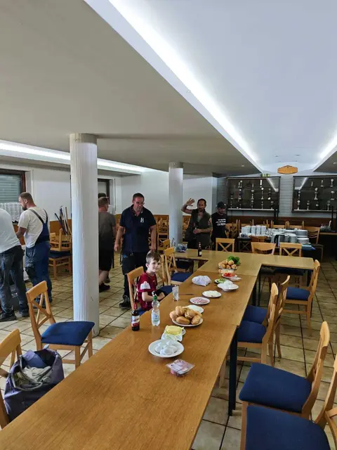 Mehrere Personen stehen an einem Tisch mit belegten Brötchen und Getränken, während sie die Verpflegung für die Helfer vorbereiten.