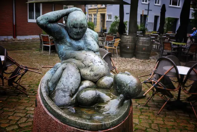 Die fröhlichen Badenden, eine Frau spuckt dem fülligen Mann auf den Bauch.