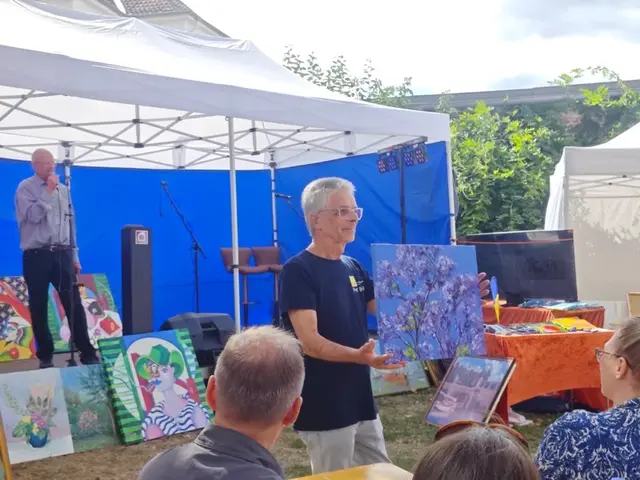 Peter Brill vom Team "ASB-Wünschewagen" mit einem Kunstwerk der Künstlerin Beatrix Kraan - im Hintergrund Auktionator Ivo Franz, 1. Vorsitzender des Kunstvereins KKRR, Ruhrstr. 3