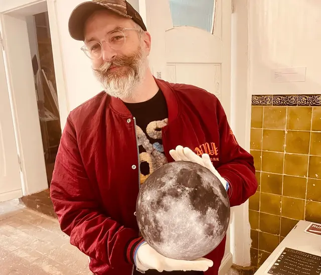 „GET YOU THE MOON“ ist ein im Jahr 2026 veröffentlichtes Kunstwerk des deutschen Digitalkünstlers und Musikers Sven Piayda. Es wurde im Rahmen der Gruppenausstellung „Open House: Kunstszene Gelsenkirchen“ im Kunstmuseum Gelsenkirchen und im MMKM Museum Moderne Kunst Mülheim präsentiert. Das Werk bricht bewusst die Grenzen zwischen klassischer Fotografie und digitaler Erstellung auf. Es zeigt keine reale astronomische Aufnahme, sondern eine vollständig am Computer generierte Bildsynthese des Mondes, die auf einer kreisrunden Aluminium-Verbundplatte fixiert ist. Dadurch entsteht ein spannender Kontrast zwischen einem hochtechnologischen, künstlichen Entstehungsprozess (CGI) und einer physisch greifbaren, edlen Galerie-Präsentation (Dibond).  Der englische Titel beschreibt das Werk präzise und wird wie folgt ins Deutsche übersetzt: „Eine kreisrunde Dibond-CGI-Fotografie, die ein Rendering des Mondes zeigt.“  Die Begriffe kurz erklärt: •	CGI photography (CGI-Fotografie): Computer Generated Imagery. Ein Bild, das wie eine echte Fotografie wirkt, aber vollständig am Computer erzeugt wurde.  •	Rendering (Bildsynthese): Der Prozess, bei dem die Software aus digitalen 3D-Daten das finale, sichtbare Bild berechnet. •	Dibond (Alu-Dibond): Ein stabiles Trägermaterial aus zwei dünnen Aluminiumschichten mit einem Kunststoffkern. In der Kunstszene verleiht es rahmenlosen Werken einen modernen, eleganten Charakter, bei dem das Motiv scheinbar vor der Wand schwebt.  •	Präsentation des Kunstwerks in hohen Räumen der Villa Artis (MMKM-Museum-Mülheim), der Blick zum Kunstwerk erinnert einen Blick auf den realen Mond.
