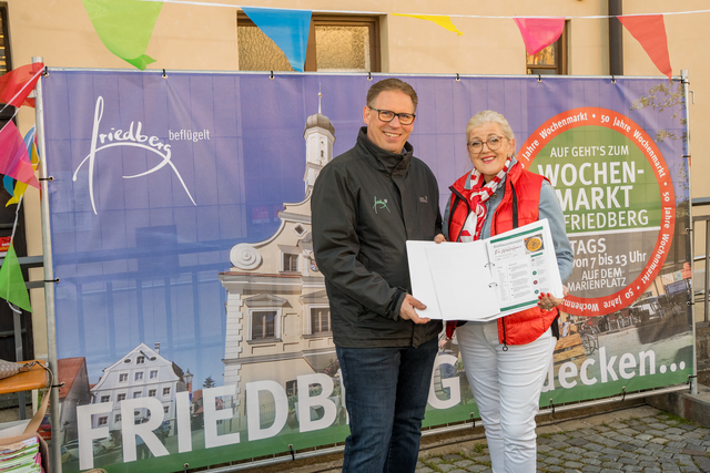 50 Jahre Friedberger Wochenmarkt - Marktmeister Roland Gerkens und Friedbergs Dritte Bürgermeisterin Ulrike Sasse-Feile haben ein besonderes Geschenk zum Jubiläum: Die kostenlose Friedberger Rezeptsammlung "Friedberg schmeckt". Darin verbinden sich Rezepte mit Produkten, die auf dem Wochenmarkt erhältlich sind, mit einem historischen Rückblick auf die Entwicklung des Marktes. | Foto: FSeventfoto