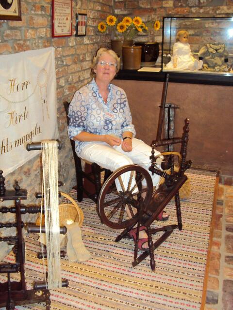 Frau Eggebrecht am Spinnrad; Dr. Eggebrecht führt währenddessen die Besucher durch die Ausstellung