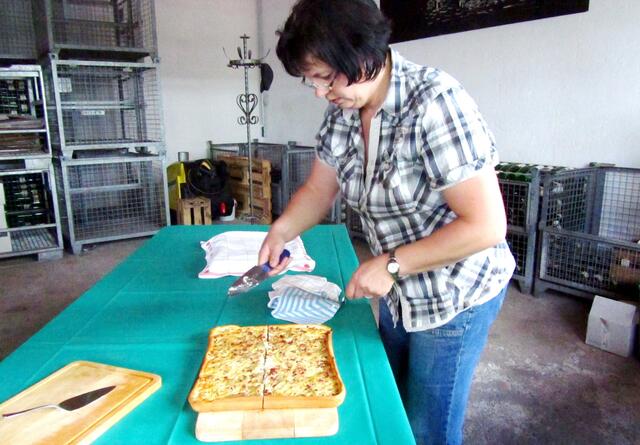 Frau Born schneidet den Zwiebelkuchen