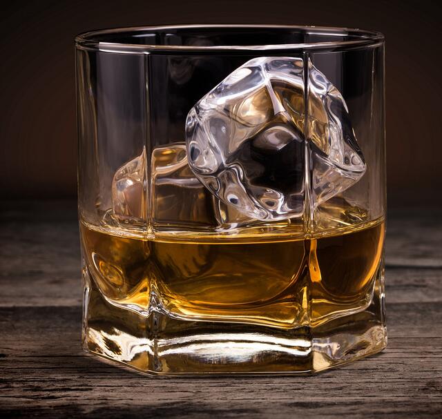 Glasses of whiskey on wood background.