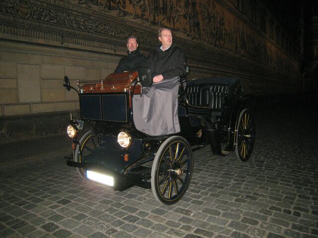 Dieses Gefährt fuhr an uns vorbei. Es war lautlos, sah sehr alt aus, hatte aber eine moderne Beleuchtung dran. Es ist eine Mischung aus Pferdedroschke und Auto ohne Markennamen am "Kühler"