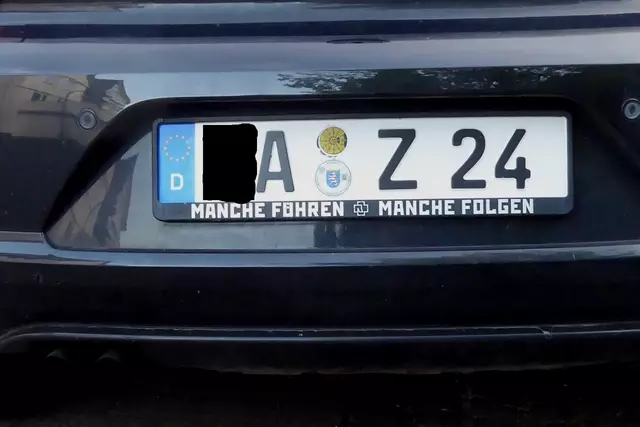 Auto-Kennzeichenhalterung für das hintere Nummernschild: 
Manche führen, manche folgen. 
Viele andere sind schon abgebogen. 
Das Signet in der Mitte ist das der Musikgruppe Rammstein.