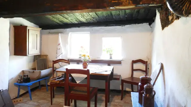 Das Pfarrwitwenhaus in Groß Zicker ist innen ebenso charmant wie geschichtsträchtig. Es handelt sich um ein niederdeutsches Hallenhaus aus dem frühen 18. Jahrhundert, das mit traditionellen Materialien wie Holz, Lehm und Rohr errichtet wurde. Die originale Zweiständerbauweise ist bis heute sichtbar und verleiht dem Inneren eine schlichte, aber eindrucksvolle Atmosphäre.
Im Inneren findest du:
- Niedrige Deckenbalken und rustikale Holzböden
- Eine Dauerausstellung, die das Leben der Pfarrwitwen und späterer Bewohnerinnen wie Anna Cadow und Anna Glutsch dokumentiert
- Räume, die mit historischen Möbeln und Alltagsgegenständen ausgestattet sind, um das frühere Leben authentisch zu zeigen
- Einen kleinen Empfangsbereich mit Informationen zur Geschichte des Hauses und wechselnden Kunstausstellungen


