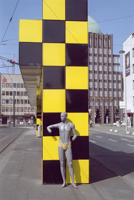 Der "Busstop" stand ursprünglich an einer Straßenbahn (Stadtbahn-) Haltestelle auf der Kurt-Schumacher-Straße. Und der Herr aus Plastik, der wohl auf eine Bahn wartete, trug eine passende Badehose.
